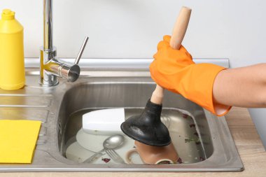 Tıkanmış mutfak lavabosunu pompayla temizleyen kadın, yakın plan.