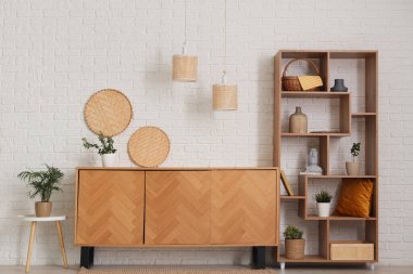 Odanın içinde ahşap tuvalet, raf ünitesi ve bitkiler var.