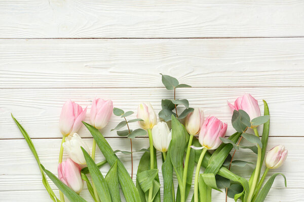 Букет красивых тюльпанов с эвкалиптом на белом деревянном фоне. Международный женский день