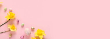 Sarı narsisli ve pembe arkaplanlı Paskalya yumurtaları.