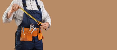 Ölçüm bandı ve kahverengi arkaplanda metin için alanı olan erkek inşaat işçisi