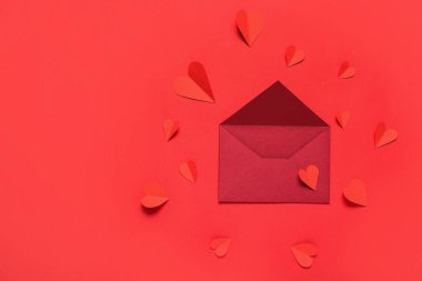 Zarflı kompozisyon ve kırmızı arka planda kağıt kalpler. Sevgililer Günü kutlaması