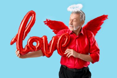 Aşk tanrısı gibi giyinmiş, mavi arka planda balonlardan yapılmış bir aşk sözcüğü. Sevgililer Günü kutlaması