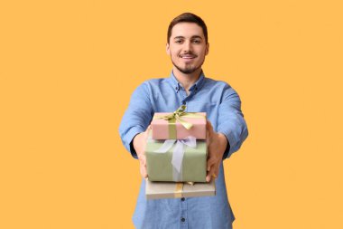 Sarı arka planda hediye kutuları olan genç bir adam. Uluslararası Kadınlar Günü