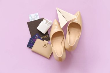 Renkli arka planda şık yüksek topuklu ayakkabılar, kulaklıklar, pasaport ve kredi kartlarıyla kompozisyon