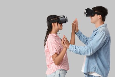 VR gözlüklü genç çift arka planda el ele tutuşuyorlar.