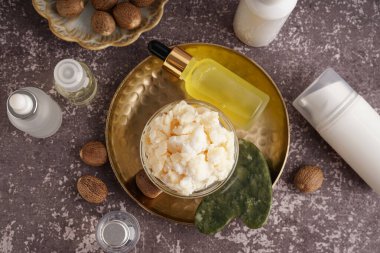 Arka planda bir kase Shea Butter ve kozmetik ürünle kompozisyon
