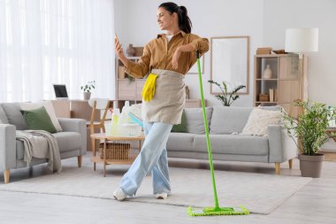 Evde cep telefonu kullanan paspasla genç bir kadın.