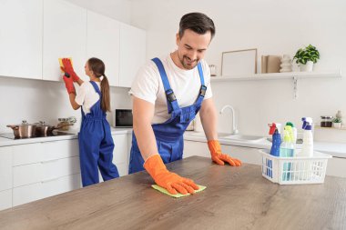 Mutfakta erkek hademe masasını temizliyor.