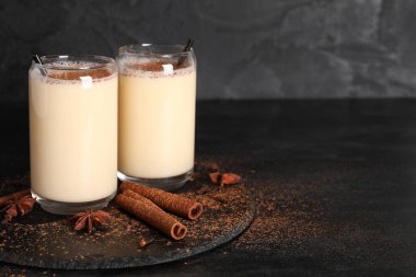Tarçınlı lezzetli eggnog kokteyli ve siyah arka planda yıldız anason.