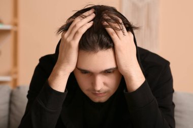 Depresyondaki genç adam evde, yakın çekim.