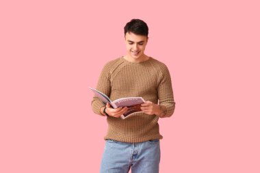 Pembe arka planda kahverengi süveter giyen yakışıklı genç adam.