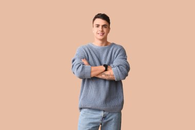 Kahverengi arka planda zarif mavi süveter giyen yakışıklı genç adam.