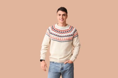 Kahverengi arka planda şık süveter giyen yakışıklı bir genç.