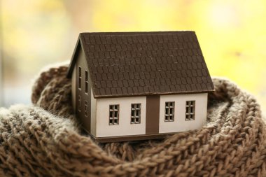 Pencerenin yanında sıcak eşarbı olan bir ev modeli. Isınma mevsimi kavramı