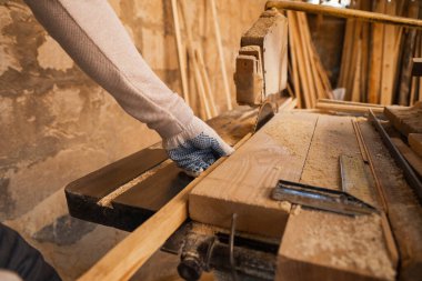 Erkek marangoz kereste fabrikasında tahta kesiyor, yakın plan.