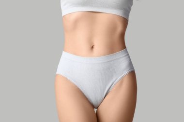 Gri arka planda beyaz iç çamaşırlı güzel bir kadın, yakın plan.