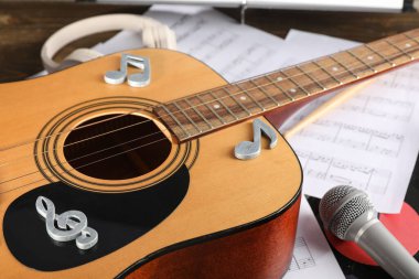 Üzerinde nota işaretleri, nota kağıtları ve mikrofon olan gitar, yakın plan.