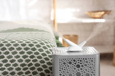 Modern nemlendirici, yatak odasındaki büyük yatağın yanında, yakın plan.