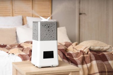 Yatak odasının yanındaki ahşap masada modern nemlendirici.