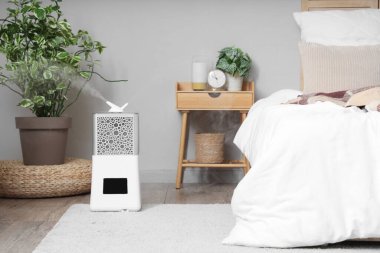 Yatak odasının yanında ev bitkileri olan modern nemlendirici.