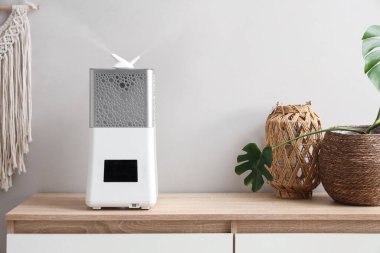 Yatak odasındaki beyaz duvarın yanında modern nemlendirici var.