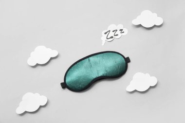 Uyku maskeli kompozisyon, kağıt bulutlar ve gri arkaplanda ZZZ mesajı. Dünya Uyku Günü konsepti