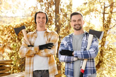 Male lumberjacks with axes in forest clipart