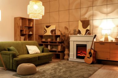 Geceleri şöminesi, gitarı ve yeşil kanepesi olan rahat bir oturma odası.