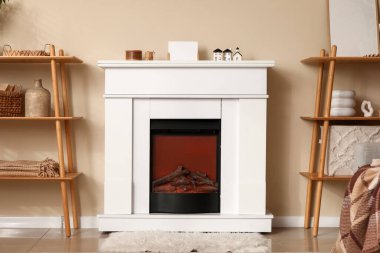 Oturma odasındaki bej duvarın yanında raf üniteleri olan modern şömine.