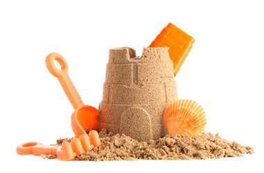 Beyaz arka planda kumdan, deniz kabuğundan ve plaj oyuncaklarından kale