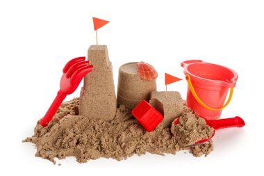 Beyaz arka planda kumdan ve plaj oyuncaklarından yapılmış bir kale.