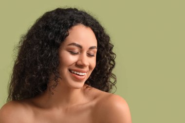 Yeşil arka planda sağlıklı bir cildi olan güzel, mutlu, Afro-Amerikalı bir kadın.