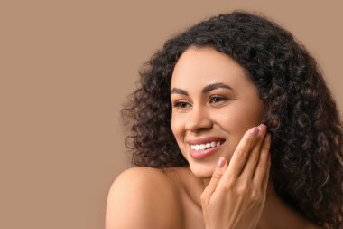 Kahverengi arka planda sağlıklı bir teni olan güzel, mutlu, Afro-Amerikalı bir kadın.