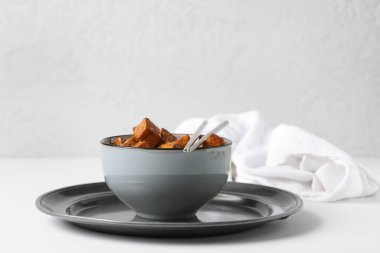 Beyaz arka planda kızarmış tofu peyniri ve metal çubuklarla dolu bir kase.