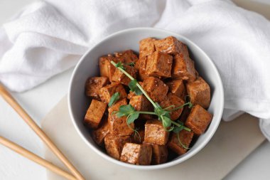 Beyaz arka planda kızarmış tofu peyniri ve mikro yeşili olan kase, yakın plan.