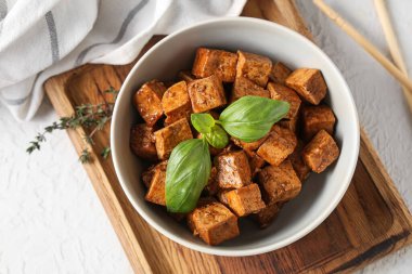 Beyaz arka planda kızarmış tofu peyniri ve fesleğenli kase, yakın plan.