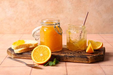 Kavanozlar dolusu tatlı portakal reçeli ve bej fayanslı ekmek dilimleri.