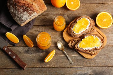 Kavanozlar dolusu tatlı portakal reçeli ve tahta arka planda dilimler.