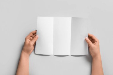 Gri arka planda boş broşürlü kadın elleri