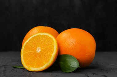 Taze portakallar ve siyah arkaplanda yapraklar