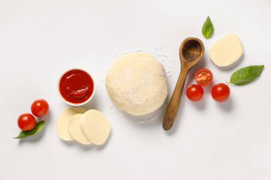 Çiğ hamur, tahta kaşık ve beyaz arka planda mozzarella ile pizza hazırlamak için malzemeler.