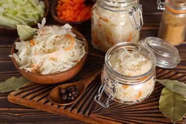 Kavanozda lahana turşusu ve ahşap masada malzemelerle dolu bir kase. Yakın çekim.