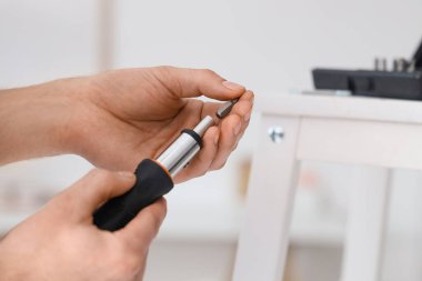 Erkek marangoz tornavida değiştiriyor. Sapını ısırıyor, yakın plan.