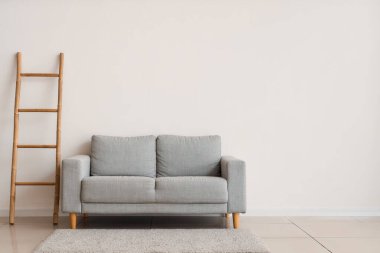 Beyaz duvarın yanında şık gri kanepe ve merdiven