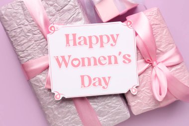 Leylak arka planında hediye kutuları olan şenlikli bir kartpostal. Mutlu Kadınlar Günü