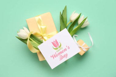 Turkuaz arka planda hediye kutuları ve lalelerle dolu bir kartpostal. Mutlu Kadınlar Günü
