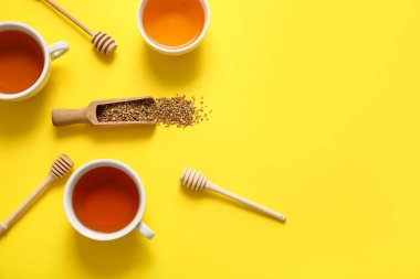 Sarı arka planda ballı sıcak karabuğday çayı ve kase