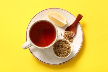 Sarı arka planda limonlu sıcak karabuğday çayı.