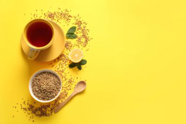 Sarı arka planda naneli ve limonlu sıcak karabuğday çayı.